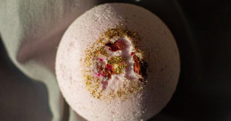 Salicylic Acid - Top view pink fragrant bath bomb in shape of ball placed on dark cloth