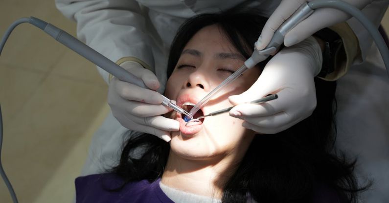 Treatments - A woman getting her teeth cleaned by a dentist